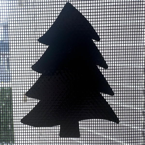 Black silhouette of a Christmas tree on a window screen