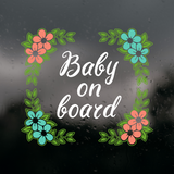 Decorative 'Baby on board' sign with flowers on a dark background