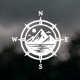 White compass with mountain design on a dark background